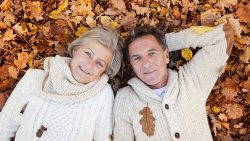 46449912 – active seniors lying on the ground in colorful autumn leaves. alternate text for this image