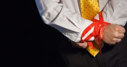 7794349 – a close up of a man in a suite with his hands tied up with red tape. alternate text for this image