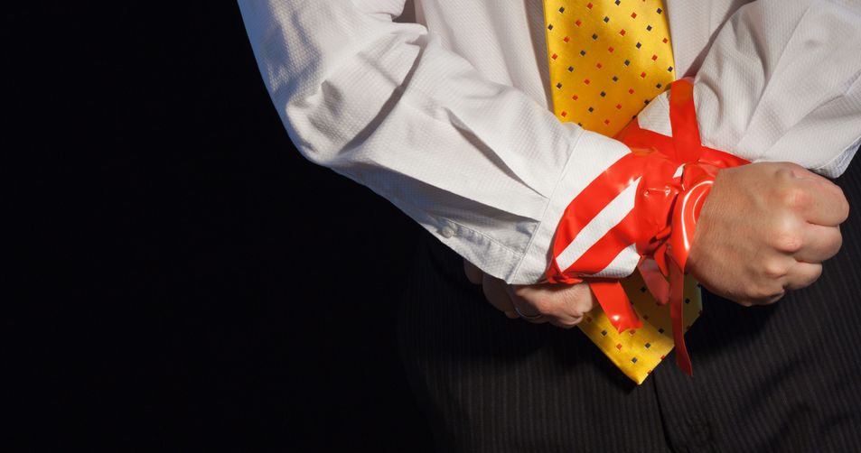 7794349 – a close up of a man in a suite with his hands tied up with red tape. alternate text for this image