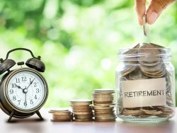 Hand putting Coins in glass jar with retro alarm clock for time to money saving for retirement