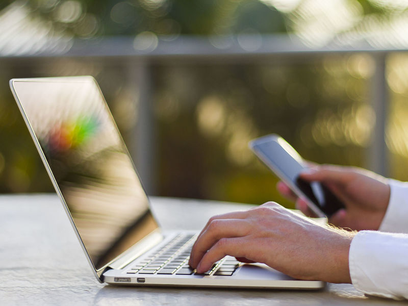 businessman working with laptop and cell phone alternate text for this image