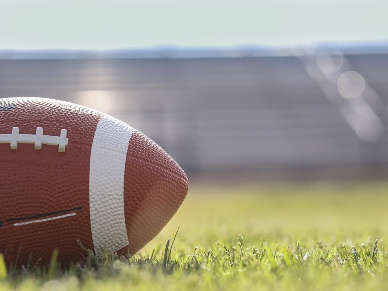 American football on stadium field at school campus. alternate text for this image