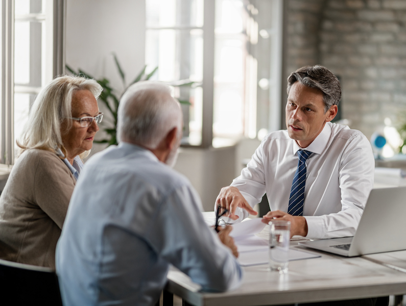 Financial advisor and senior couple talking while going through paperwork on a meeting. alternate text for this image