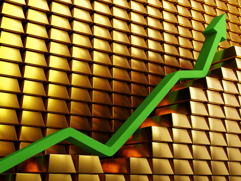 Gold prices soaring in a bullish market. Green arrow going up over gold bars. Concept digital 3D render. alternate text for this image