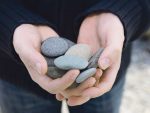 Hand offering rounded pebbles