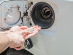 Close up on man's hands counting his money at gas station with car gas door open