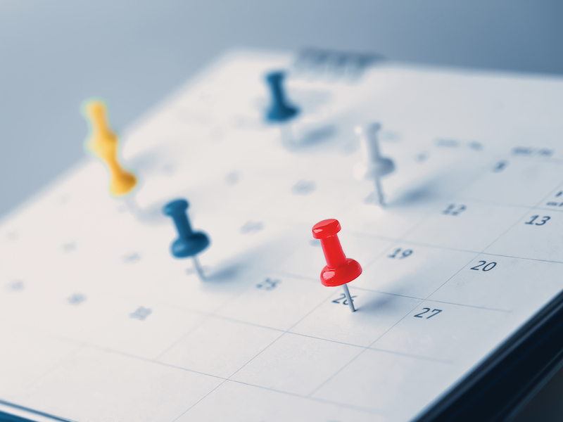 Embroidered red pins on a calendar event Planner calendar,clock to set timetable organize schedule,planning for business meeting or travel planning concept. alternate text for this image